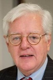 An older man with white hair and glasses in a suit